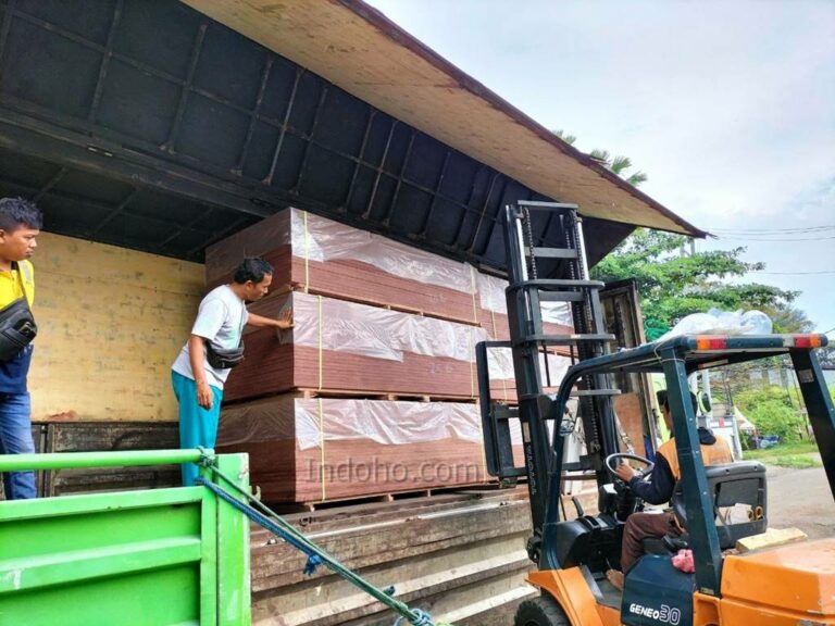 Proses bongkar muat plywood film face menggunakan forklift di area gudang distribusi